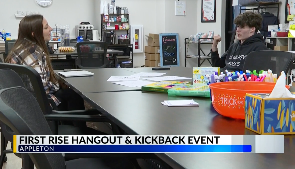 A young woman and a young man are engaged in conversation during the first RISE Hangout and Kickback event, which features a snack table and an array of craft supplies in a community room in Appleton.