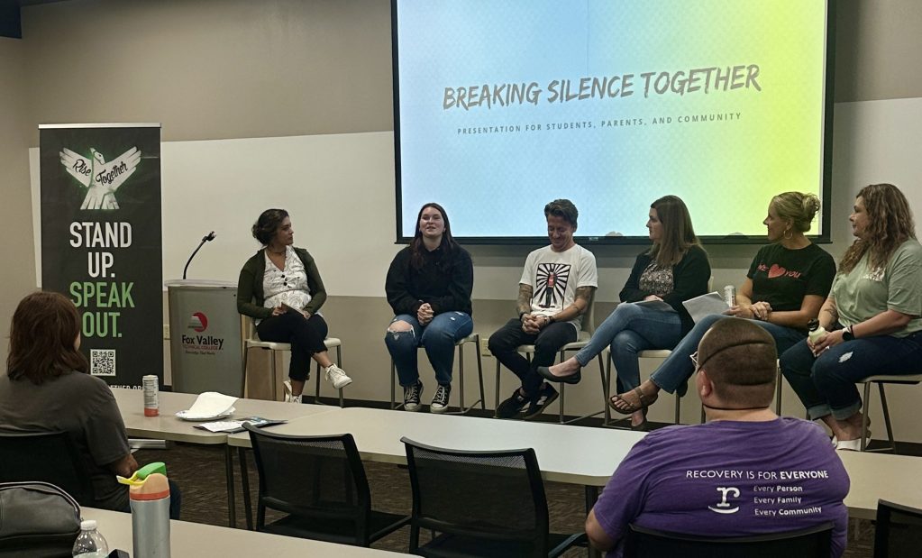 A group of speakers discussing mental health and substance use prevention at a RISE TOGETHER presentation. The backdrop features the slogan 'Breaking Silence Together'.